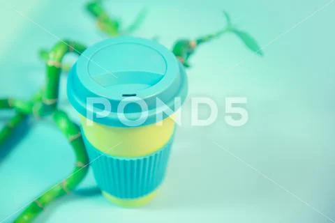 Zero waste concept. Stylish reusable eco coffee cup and green bamboo leaves. Stock Photos