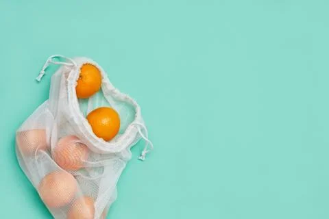 Zero waste concept. Tangerines in the package. Copyspace. Green background. Stock Photos