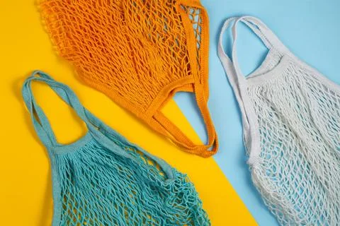 Zero waste concept. Three mesh shopping bags lie on yellow blue background Stock Photos