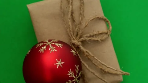 Zero waste gift with red Christmas tree ball spins on green background Stock Footage 224639601