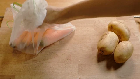 Zero waste lifestyle concept. Pull off carrots and potatoes of the reusable b Stock Footage 107262456