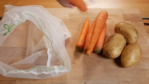 Zero waste lifestyle concept. Pull on carrots and potatoes of the reusable ba Stock Footage 107262587