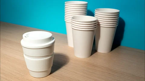ZERO WASTE: One reusable mug and a many paper cups on a table - Stop motion Видео 155365385