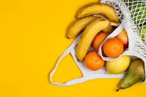Zero waste plastic free concept. Fresh fruit in a mesh net bag, top view with Stock Photos