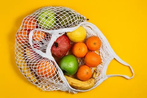 Zero waste plastic free concept. Fresh fruit in a mesh net bag, top view with Stock Photos