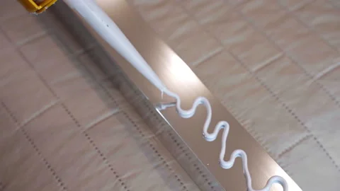 Zig zag white glue applying on metal profile surface, workman using industrial Stock Footage 224726861