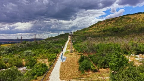 Zip line course stretches across a hillside with trees and cloudy sky in the Stock Footage 341398295