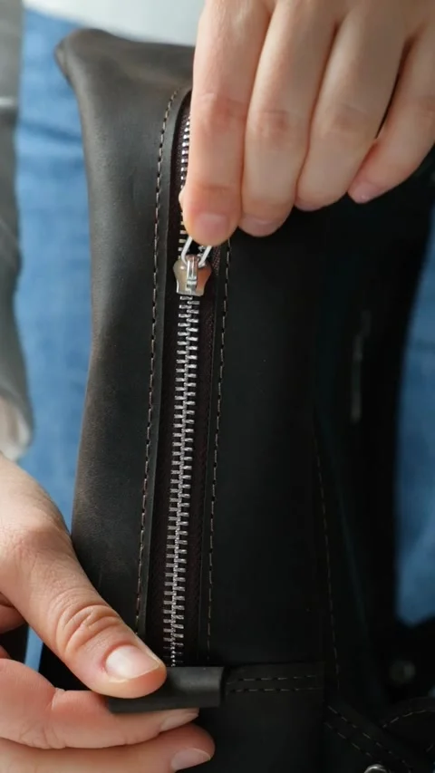 Zip up metal zipper on leather backpack, vertical slow motion Stock Footage 292657050