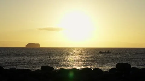 A zodiac cuts across the reflections of the setting sun in The Galápagos Stock Footage 342119105