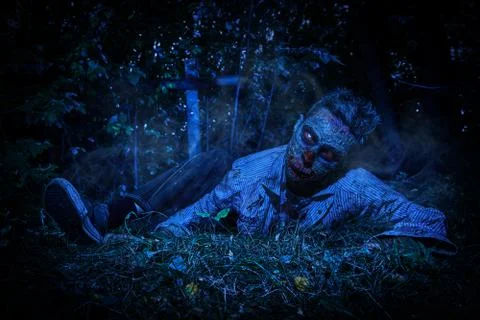 Zombie climbs out of the grave in the night cemetery. Halloween. Horror. Stock Photos