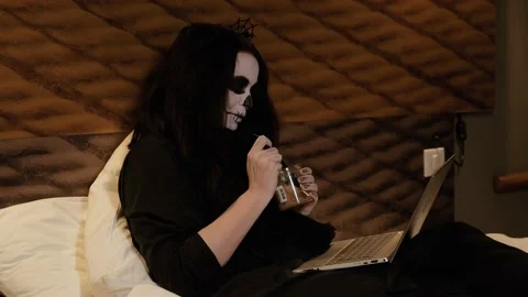 Zombie girl eats brain jam, looks at a laptop and laughs. Halloween eve. Stock Footage 141899491