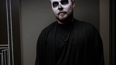 A zombie man with makeup on his face is standing against the wall. Halloween Eve Stock Footage 142075411