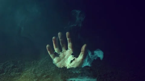 The zombie's hand comes out from under the ground and scares with gestures. Stock Footage 214769135