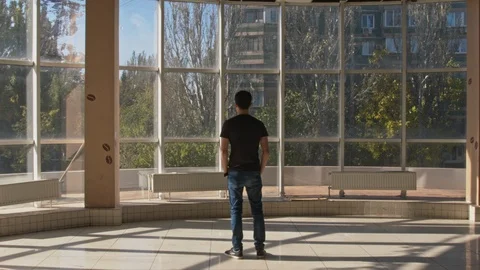 Zoom In From the Back On A Young Man Standing in Front of a Huge Window Stock-Footage 92936657