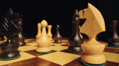 Zoom in between chess pieces on a chessboard with knight in foreground Stock Footage 149316704