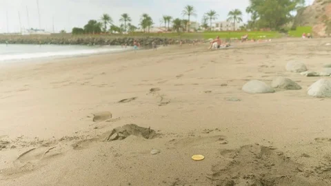 Zoom in of bitcoin lying on sand with blurred people resting on beach on Video stock 84871607
