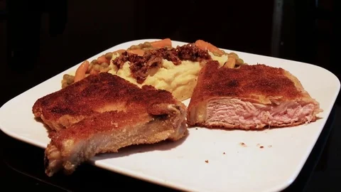 Zoom breaded veal cutlet mashed potatoes roasted onions peas carrots Stock Footage 70313736