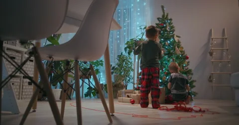 Zoom camera: Two boys decorating a Christmas tree on Christmas Eve wearing Video stock 146225594