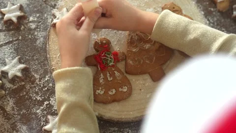 Zoom on child hands decorating ginger homemade biscuits on a wooden plate, view Stock Footage 256969068
