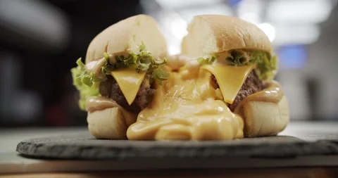 Zoom in on cut burger from which cheese leaked. Slow motion video 4K Stock Footage 120512637