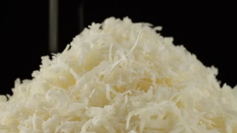 Zoom frame sprinkle grated parmesan cheese close-up, black background Stock Footage 250610146