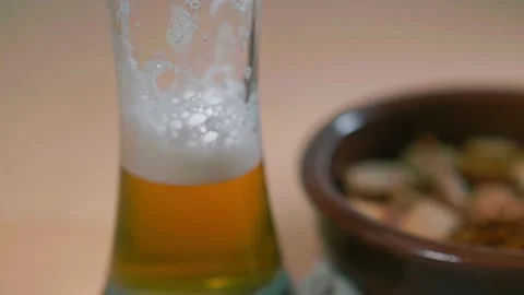 Zoom in of a glass of beer standing on the table and the beer pouring into it Stock-Footage 166120092
