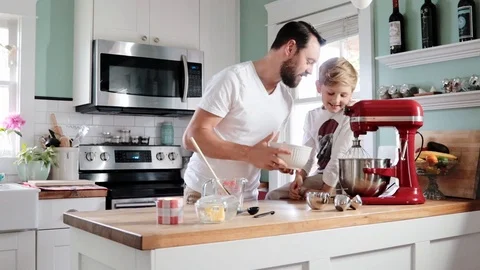Zoom in handheld shot of father and son cooking with electric mixer in kitchen Stock Footage