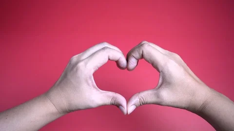 Zoom in hands making heart shape on red background. 스톡 동영상 128390510