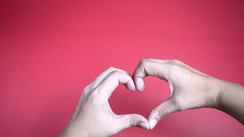 Zoom in hands making heart shape on red background. 스톡 동영상 128391046