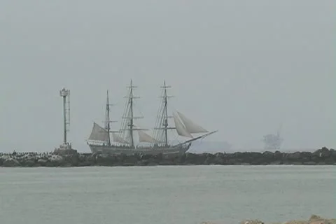 Zoom into HMS Bounty sailing outside of breakwater Stock Footage 12456397