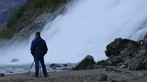 Zoom-Man monitors camera on tripod taking video of rushing waters Stock Footage 208812190