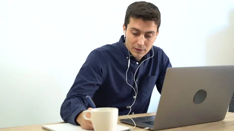 Zoom in of a man teleworking from home making a video conference and writing. Stock Footage 147655172