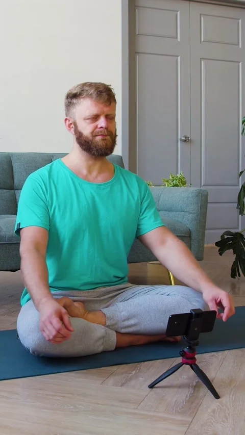 Zoom in of a middle-aged man picking up an online workout guide for his home Stock Footage 325773123