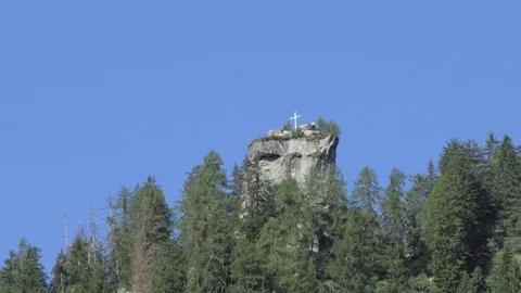 Zoom in of a mountain summit with rotating glasses on a cross moved by the wind Video stock 112750935