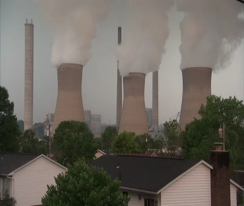 Zoom out from 3 smoking cooling towers to suburban ranch homes Stock-Footage 86694930