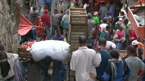 Zoom out above crowded African city market, men walking carry heavy loads Stock-Footage 10982559
