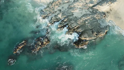 Zoom out aerial view of waves with sea foam splashing on big coastal Stock Footage 242178982