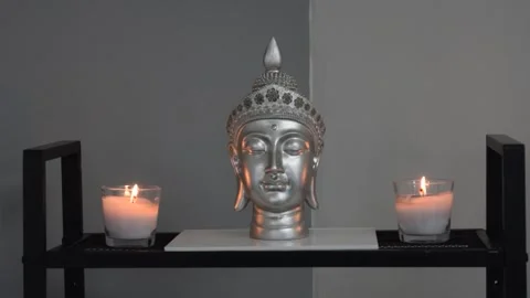 Zoom out of Buddhist altar with silver buddha head and lighted candles Stock Footage 159449152