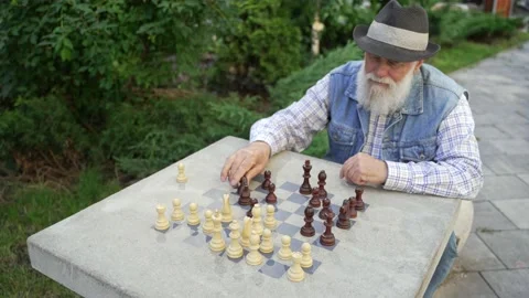Zoom out concentrated elderly man makes chess move Stock Footage 207200414