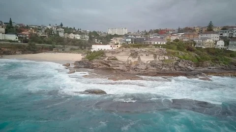 Zoom out drone shot of waves crashing on coastline overlooking cityscape Stock Footage 122448509