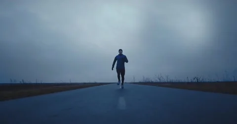 Zoom out dynamic shot of athlete man running fast down empty long road, getting Video stock 148331633