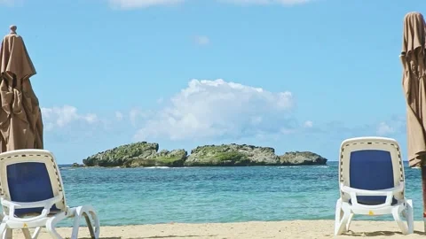 Zoom out from empty sandy seashore with long beach chairs and closed umbrellas Video stock 130664131