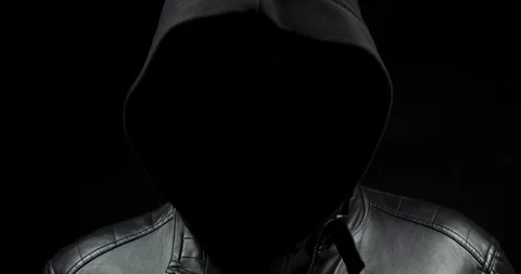 Zoom out of a faceless hooded hacker man in the shadows wearing a leather jacket 스톡 동영상 328319783