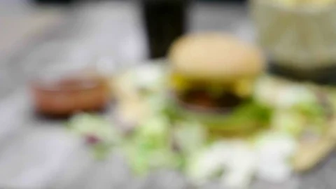 Zoom in from out of focus on home made hamburger with fries on wooden table Stock Footage 83787436