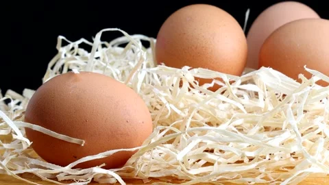 Zoom out of fresh and raw eggs on a bed of straw Stock Footage 184435703
