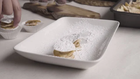 Zoom out of hand removing leaf litter alfajores from the powdered sugar sifting  Stock Footage 240310656