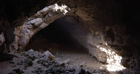 Zoom out of Light streaming through hole in cave ceiling Stock Footage 220953176