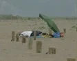 Zoom out from man lying on beach under shade SD Footage