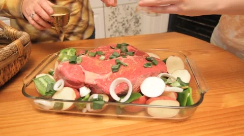 Zoom out from meat dish as two women prepare it and putting it in  oven Stock Footage 45523873