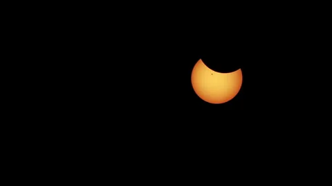 Zoom-out of partial solar eclipse with sunspot visible on the face of the Stock Footage 272406334